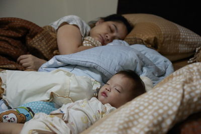 Mother and son sleeping on bed at home