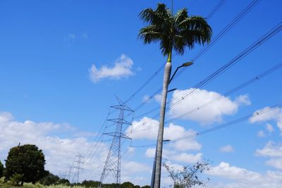 Low angle view of electricity pylon against blue sky