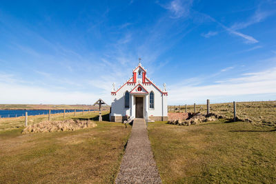 Built structure on landscape against blue sky