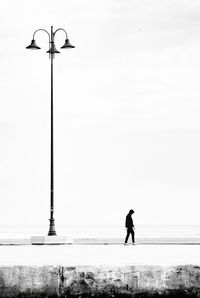 Silhouette man standing on street against clear sky