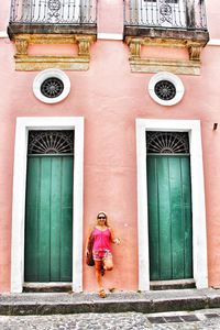 Woman standing by window of building