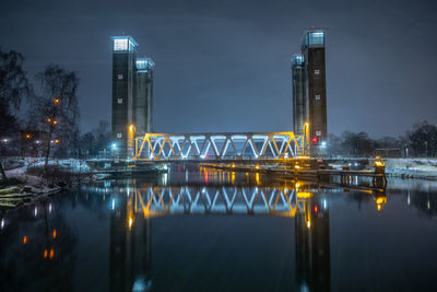 Illuminated bridge over river at night