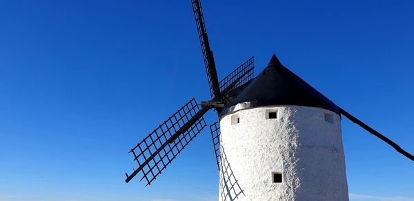 Low angle view of traditional windmill against clear blue sky