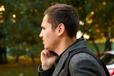 Side view of young woman looking away while standing outdoors
