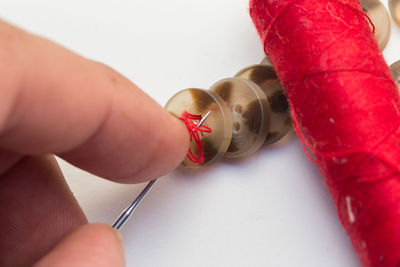 High angle view of person hand holding buttons in needle on table