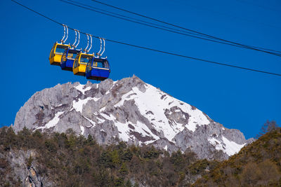 Low angle view of overhead cable car against clear blue sky