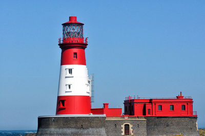 Lighthouse by sea against sky