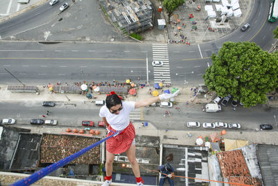 Caucasian woman wearing hero costume descending a tall building in rappel. salvador bahia brazil.