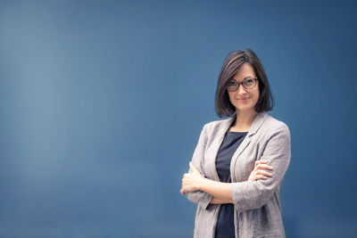 Portrait of confident businesswoman standing against colored background