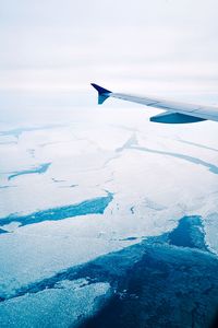 Close-up of airplane wing over sea during winter
