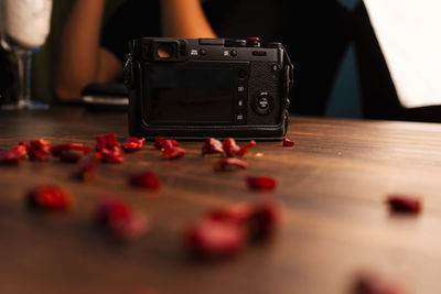 Close-up of camera and petals on table against person