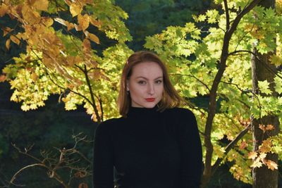 Portrait of young woman standing against plants