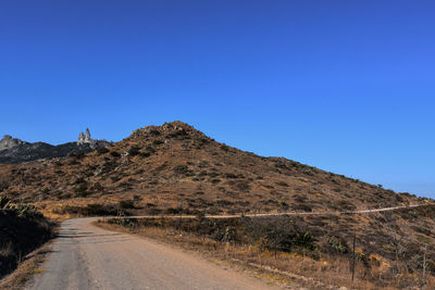 Road by mountain against clear blue sky