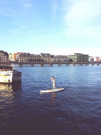 Man in boat on sea against buildings in city