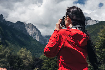 Rear view of woman standing on mountain against sky