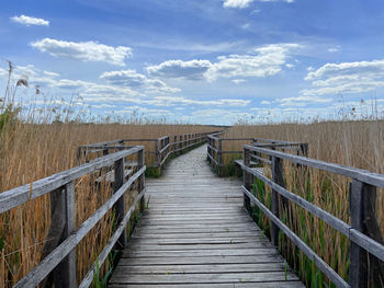 Wooden footbridge against sky