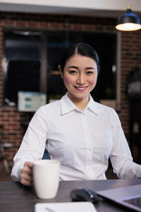 Portrait of young businesswoman using mobile phone at table