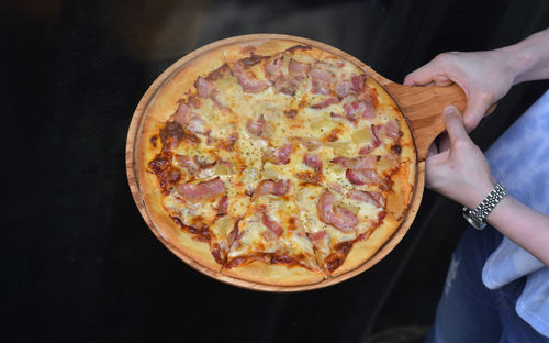 Cropped hand of man holding pizza