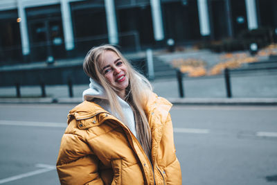 Portrait of young woman wearing warm clothing standing on road in city