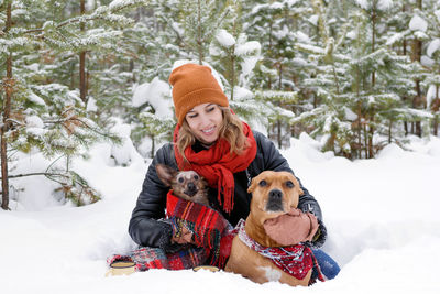 Woman with dogs on snow field against trees during winter