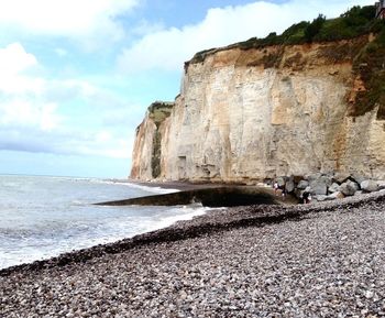 Scenic view of beach against cloudy sky