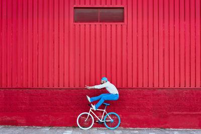 Man riding bicycle on red wall