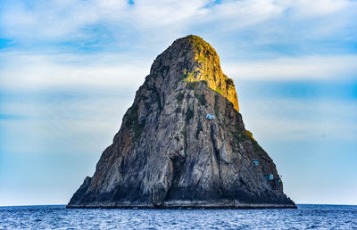 Rock formation by sea against sky