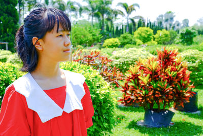 A young woman wearing a red shirt is vacationing in an outdoor park.