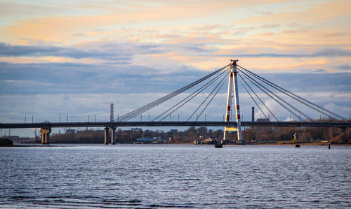 Bridge over calm sea against sky during sunset