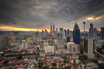 Distant view of petronas tower against cloudy sky during sunset in city