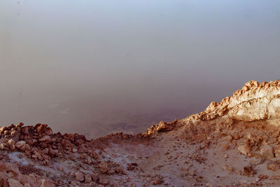 Scenic view of rocks by sea against sky