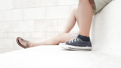 Low section of people sitting on steps by wall