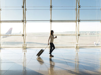 Woman walking with suitcase at the departure hall of the airport.