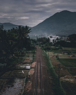 Railroad tracks by mountain against sky