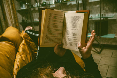 High angle view of woman reading book on sofa