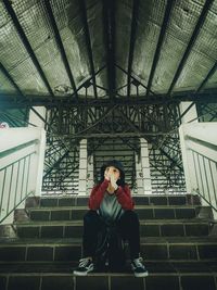 Full length of woman sitting on staircase