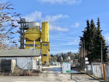 Metallic structure by factory against sky