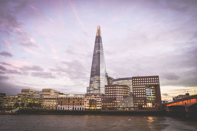 View of buildings at waterfront against cloudy sky