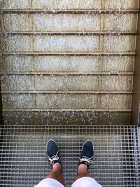 Man standing on metal grate in front of falling water