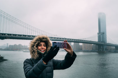 Smiling woman photographing while standing in city