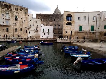 Sailboats moored on canal against buildings in city