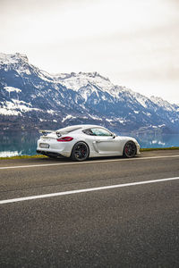 Cars on road against snowcapped mountains against sky