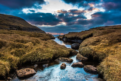 A narrow water channel in the mountain field against a cloudy sky. high quality photo