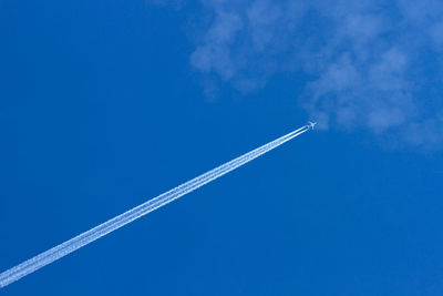 Low angle view of airplane flying against clear blue sky