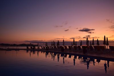 Resort by lake against sky during sunset