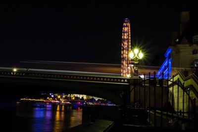 Illuminated bridge over river against sky at night