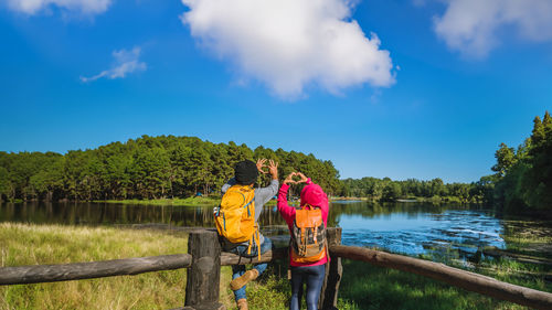 Rear view of man standing by lake against sky