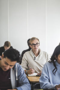 Young man writing in book at desk in classroom