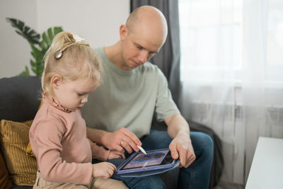 Mother and daughter sitting on sofa at home