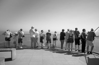 Rear view of people standing at observation point against sky